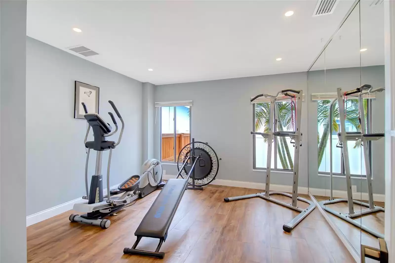 Home gym with mirrored wall, built-in shelving and storage cupboard